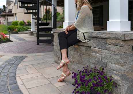 Person Sitting on Retaining Wall with Pillars and Circular Patio Design