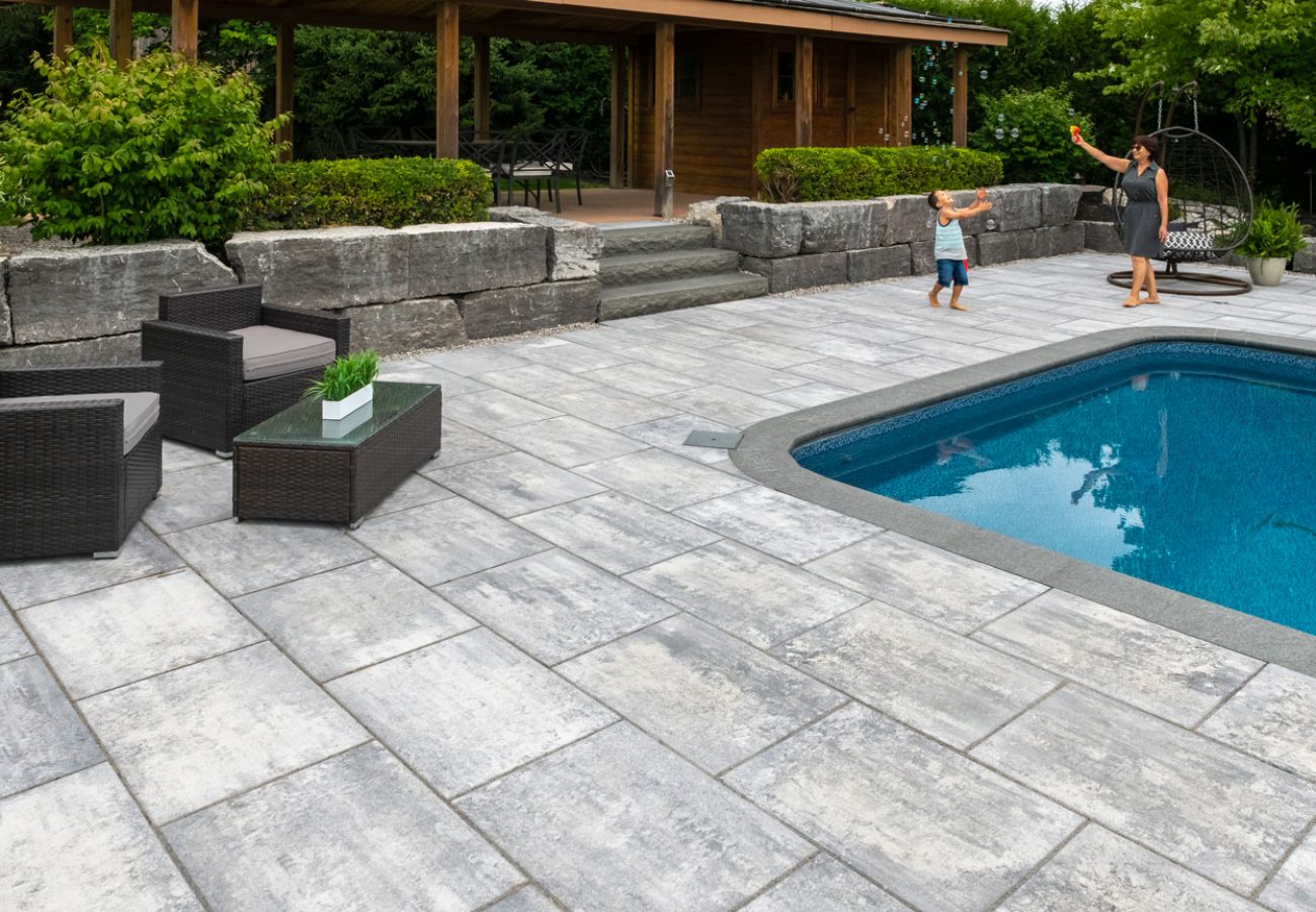 Person playing with bubbles with a child on Unilock Pool Deck