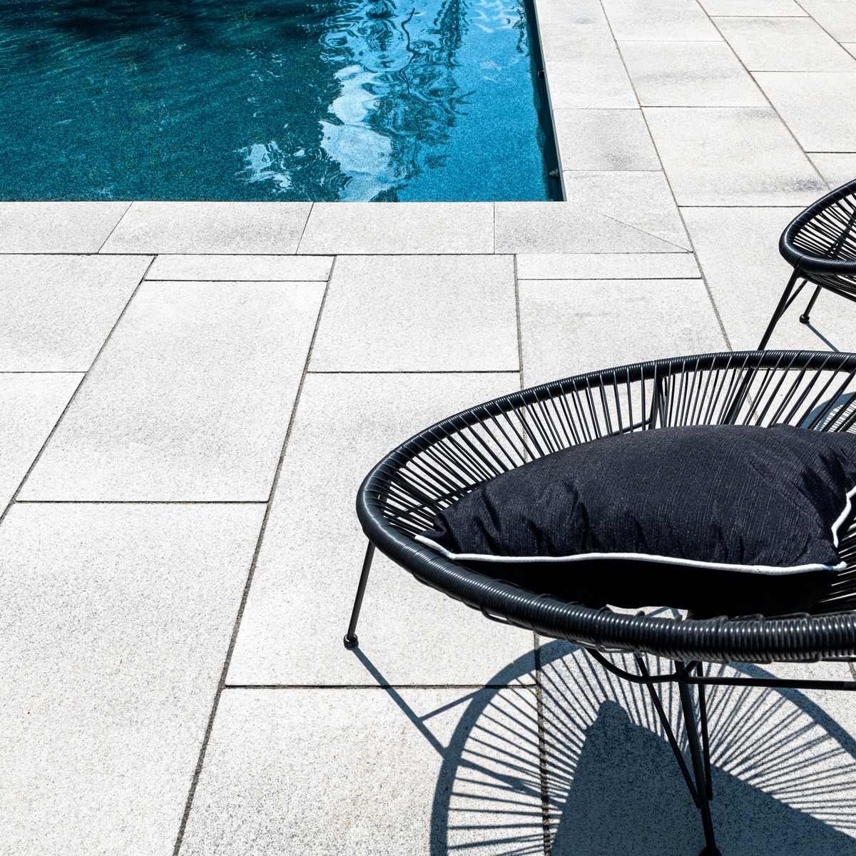 Swivel chair near pool deck on large concrete pavers